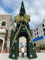 pequeno menina carrinhos perto a Natal árvore com a arco e uma arco foto