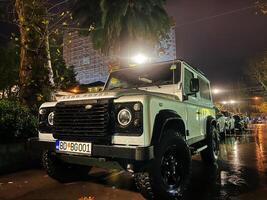 budva, Montenegro - 25 dezembro 2022. branco suv carrinhos dentro a estacionamento muitos debaixo uma rua lâmpada. logotipo. terra Andarilho foto