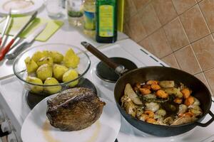 assado carne mentiras em uma prato Próximo para uma panela com legumes e uma tigela do batatas foto