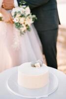noivo abraços noiva perto a Casamento bolo em uma ficar de pé em a mesa. cortado. sem rosto foto
