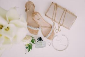 Casamento anel mentiras em uma branco mesa perto a noiva sapato, Bolsa e perfume. topo Visão foto