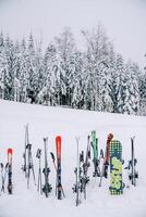 colorida pranchas de snowboard e esquis ficar de pé preso dentro a neve às a Beira do a floresta foto