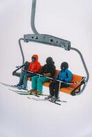 esquiadores dentro esqui ternos e capacetes passeio em uma teleférico para uma nebuloso montanha foto