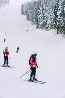 esquiadores dentro colorida esqui ternos ir baixa uma coberto de neve íngreme declive foto