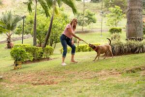 mulher com dela cachorro dentro a parque, jogando com a coleira. foto