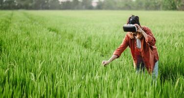 absorta dentro uma virtual realidade experiência, uma mulher alcança baixa para toque a exuberante Relva dentro uma campo, Misturando a digital e natural os mundos. foto