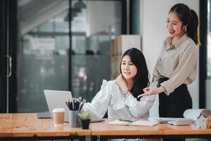 dois profissional mulheres se empenhar dentro uma colaborativo discussão às uma bem organizado escritório mesa, com 1 sentado e a de outros de pé, partilha uma momento do amigáveis interação. foto