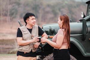 casal goza uma esquentar, alegre café pausa junto, partilha sorrisos e conversação ao lado seus fiel fora estrada carro dentro uma rural contexto. foto