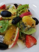 saudável Oliva e misturado fruta salada em branco prato foto
