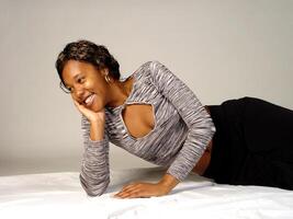 jovem africano americano mulher reclinável dentro cinzento topo foto