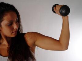caucasiano mulher braço segurando Preto peso mostrando muscel foto