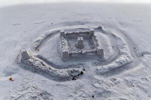 areia castelo em de praia erodido de retornando água com pé impressões foto