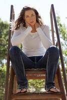 jovem mulher sentado topo do escada jeans branco topo foto