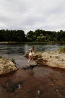 caucasiano adolescente menina às rio dentro branco malha a partir de costas foto