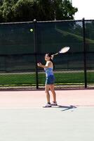hispânico adolescente menina servindo tênis bola com raquete foto