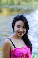 jovem japonês americano mulher molhado às rio dentro vestir foto