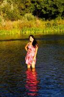 japonês americano mulher em pé dentro rio Rosa vestir foto