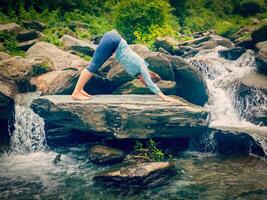 jovem desportivo em forma mulher fazendo ioga portas às tropical cascata foto