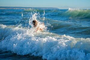 Garoto tendo Diversão pulando dentro oceano mar ondas foto