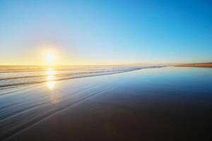 atlântico oceano pôr do sol com surgindo ondas às fonte da telha praia, Portugal foto