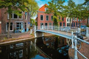 bicicleta em ponte e canal com carros estacionado ao longo dentro delft rua foto