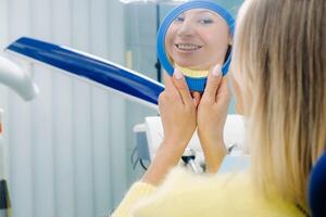 a menina sorrisos e parece dentro a espelho dentro odontologia foto