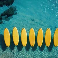 ai gerado uma conjunto do amarelo pranchas de surf em uma azul mar fundo foto