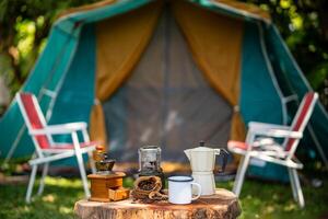 seletivo foco do vintage café conjunto em a velho de madeira mesa dentro frente do a retro cabine barraca, retro cadeiras, grupo do acampamento tendas, e suave foco. foto