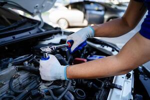 uma mecânico é trabalhando em uma carro motor, usando uma chave inglesa para afrouxar uma parafuso. conceito do foco e determinação Como a mecânico trabalho para consertar a carro foto