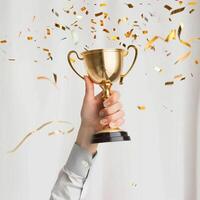 ai gerado mãos do o negócio mulher segurando e lift uma dourado troféu, em torno da com Parabéns confete fita flocos. foto