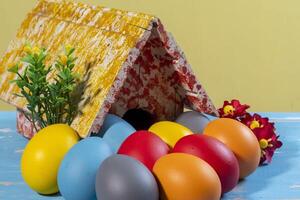 colorida ovos simbolizando páscoa, com uma brinquedo casa, flores gostar uma jardim foto