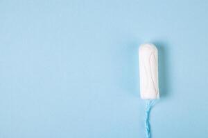 tampão de algodão higiênico sobre fundo azul. produtos de higiene menstrual feminina. foto