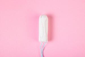 tampão de algodão higiênico em fundo rosa. produto de higiene menstrual feminina. foto