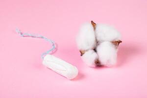 higiênico tampão e algodão flor em Rosa fundo. feminino menstrual higiene produtos. foto