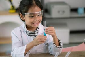 pequeno fofa menina com uma microscópio segurando uma laboratório garrafa com água experimentar estude cientistas às escola. Educação Ciência conceito. foto