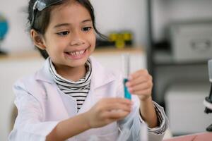 pequeno fofa menina com uma microscópio segurando uma laboratório garrafa com água experimentar estude cientistas às escola. Educação Ciência conceito. foto