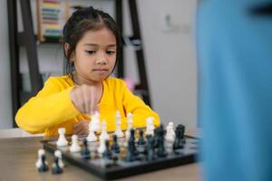 uma jovem menina é jogando uma jogos do xadrez com uma homem foto