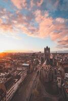 assistindo a pôr do sol sobre Gent a partir de a histórico torre dentro a cidade Centro. romântico cores dentro a céu. vermelho luz iluminador Gante, flandres região, Bélgica foto