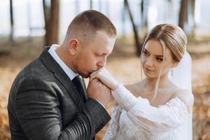 a noivo Beijos a da noiva mão. Casamento foto do uma casal dentro amar. uma jovem e bonito homem se beijando dele da esposa mão com uma ouro anel, propondo.