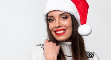 fechar acima retrato lindo caucasiano mulher dentro vermelho santa chapéu em branco estúdio fundo. Natal e Novo ano feriado conceito. foto