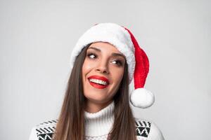 fechar acima retrato lindo caucasiano mulher dentro vermelho santa chapéu em branco estúdio fundo. Natal e Novo ano feriado conceito. foto