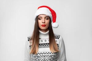 fechar acima retrato lindo caucasiano mulher dentro vermelho santa chapéu em branco estúdio fundo. Natal e Novo ano feriado conceito. foto