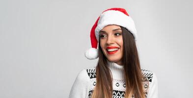 fechar acima retrato lindo caucasiano mulher dentro vermelho santa chapéu em branco estúdio fundo. Natal e Novo ano feriado conceito. foto