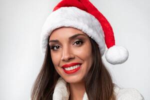 fechar acima retrato lindo caucasiano mulher dentro vermelho santa chapéu em branco estúdio fundo. Natal e Novo ano feriado conceito. foto