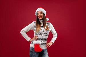 fechar acima retrato lindo caucasiano mulher dentro vermelho santa chapéu em vermelho estúdio fundo. Natal e Novo ano feriado conceito. foto