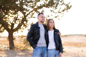 feliz e fofa adorável adulto casal do milenar descolados, homem com mulher namorada andando, ter Diversão jogar, risada e saltar em pôr do sol às deserto foto