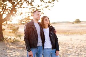 feliz e fofa adorável adulto casal do milenar descolados, homem com mulher namorada andando, ter Diversão jogar, risada e saltar em pôr do sol às deserto foto