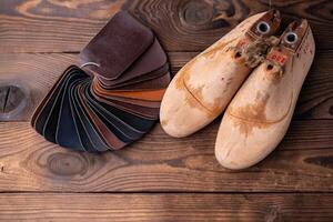 couro amostras para sapatos e de madeira sapato último em Sombrio de madeira mesa. foto