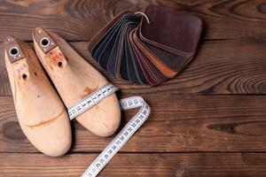 couro amostras para sapatos e de madeira sapato último em Sombrio de madeira mesa. foto