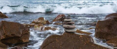 pirâmide do pedras em uma fundo mar do ampla pedras e água foto